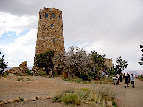 A tower build of stone blocks with people alongside