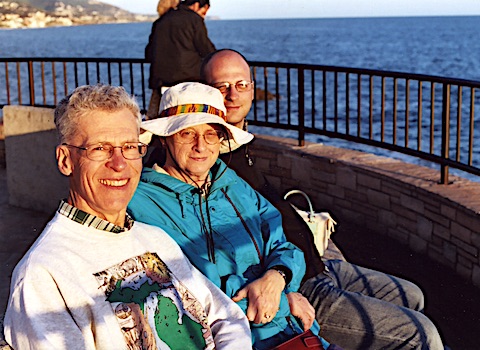 Al, Gail, and Doug illuminated by the                setting sun with the ocean behind them. 