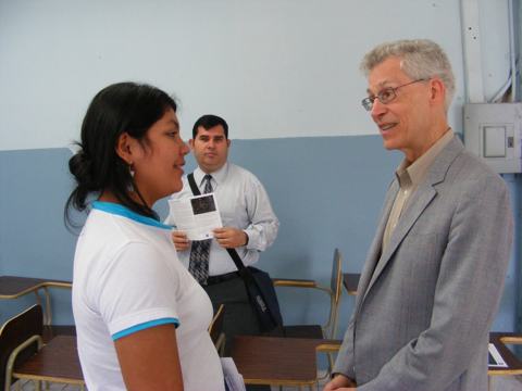 Al talks with a student in the lecture hall.                   A faculty member waits in the background.