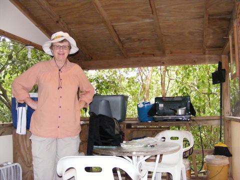 Gail in our kitchen area with
   a Colman stove, a box for food and a cooler behind her