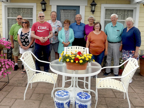 Descendents and guests are standing in front of Marks little house,            a converted garage where some of his antiques are displayed