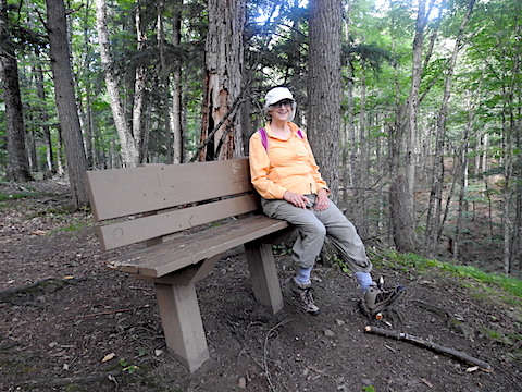 Gail is sitting on the bench withh hher dangling feet far from the ground