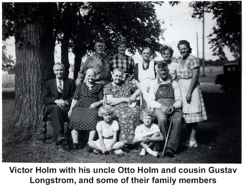 The people at the reunion are outside, with some sitting in a            row of chairs, others standing behind them, and two young girls           on the ground in front.